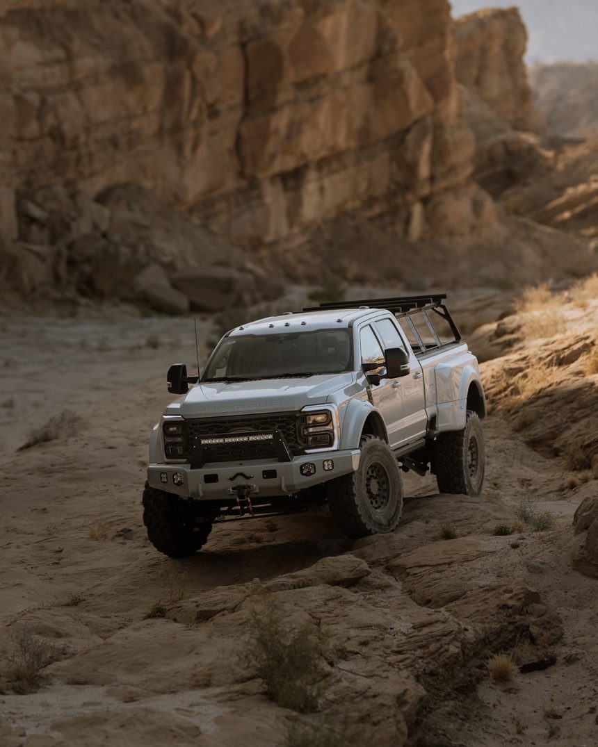 White Truman F-450 climbing a rock ledge